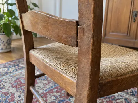 Détail du raccord entre le montant et la traverse d’une chaise ancienne, avec un jour visible dans l’assemblage
