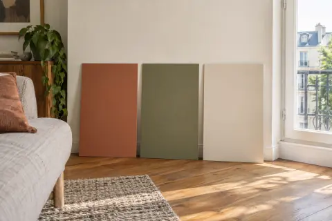 Trois échantillons de teintes terreuses posés près d’une fenêtre dans un salon clair