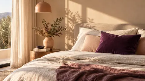 Chambre beige avec un unique coussin violet sur le lit